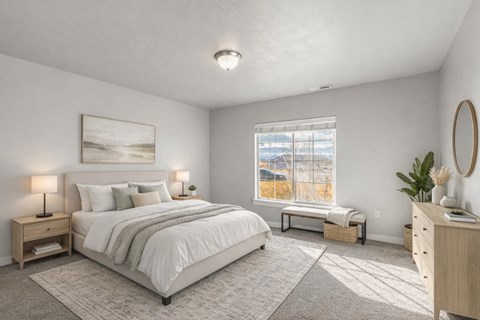 A well-lit bedroom with a large bed and a window showing a view of a snowy landscape outside.