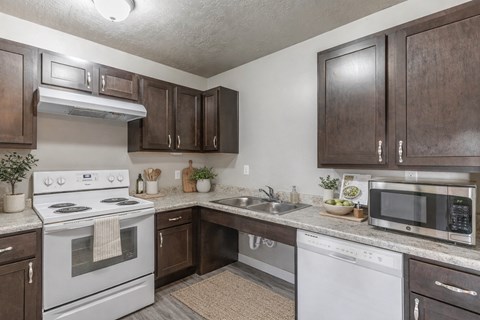 A kitchen with white appliances and brown cabinets.