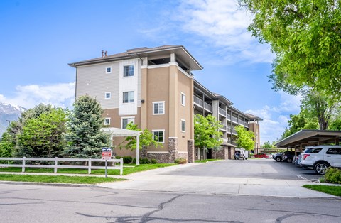 A large apartment building with a white fence in front.