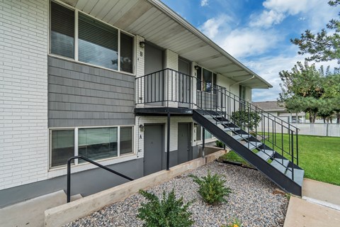 A house with a grey siding and a black metal staircase.
