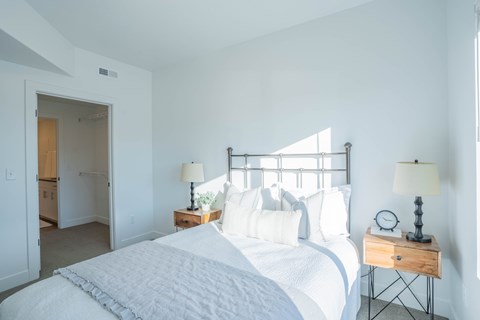 A bedroom with a large bed and two lamps.