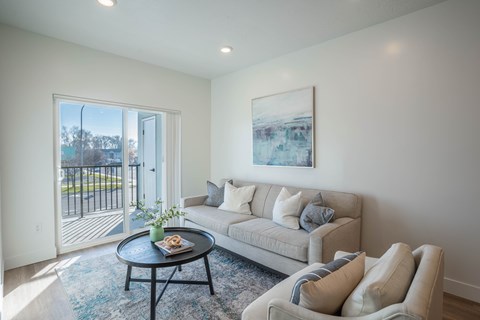 A living room with a grey couch and a small table with a plant on it.