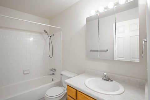 A white bathroom with a toilet, sink, and bathtub.