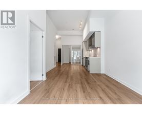 A spacious room with wooden flooring and white walls.