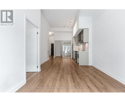 A spacious room with wooden flooring and white walls.