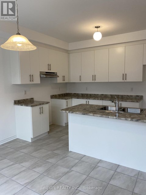 A kitchen with white cabinets and a marble countertop.