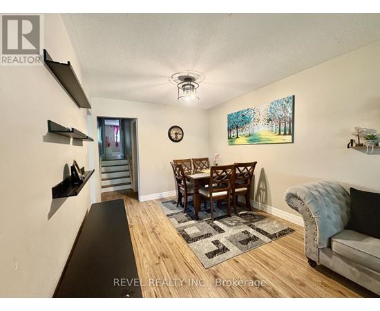 A living room with a couch, chairs, and a painting on the wall.