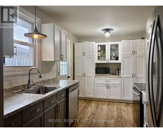 A kitchen with white cabinets and a stainless steel refrigerator.