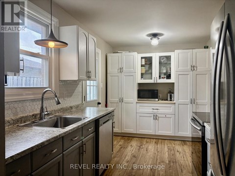 A kitchen with white cabinets and a stainless steel refrigerator.