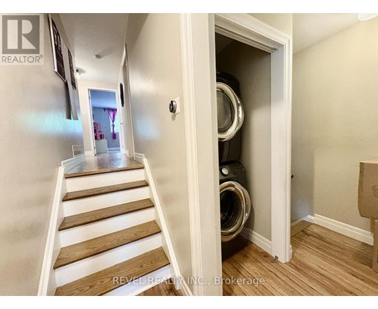 A hallway with a staircase leading to a laundry room.