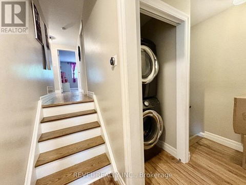 A hallway with a staircase leading to a laundry room.