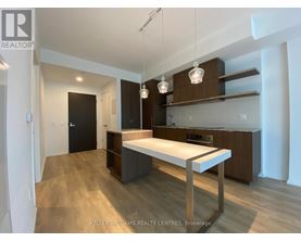 A modern kitchen with a long white island in the middle.