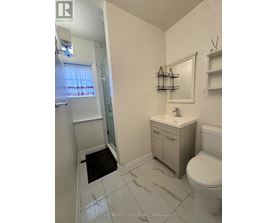 A white bathroom with a toilet, sink, and mirror.