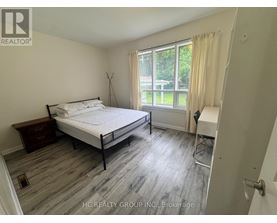 A bedroom with a bed, nightstand, and chair.
