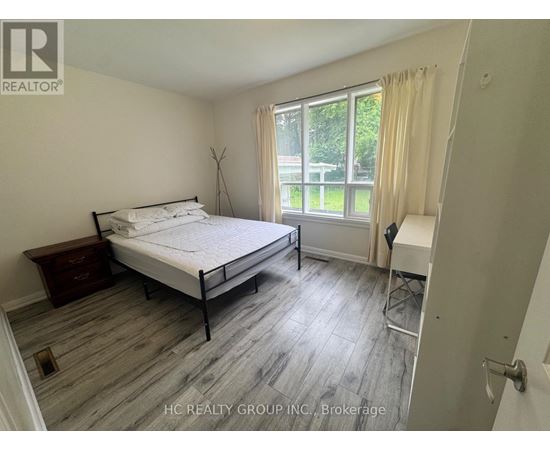 A bedroom with a bed, nightstand, and chair.