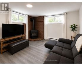 A living room with a black couch, a wooden entertainment center, and a fireplace.