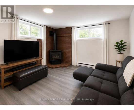 A living room with a black couch, a wooden entertainment center, and a fireplace.