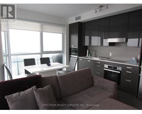 A modern kitchen with dark cabinets and a maroon couch.