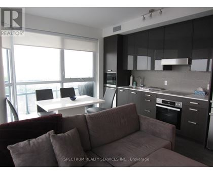 A modern kitchen with dark cabinets and a maroon couch.