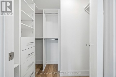 A white bedroom with a built in wardrobe and drawers.