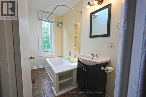A bathroom with a tub, sink, and mirror.