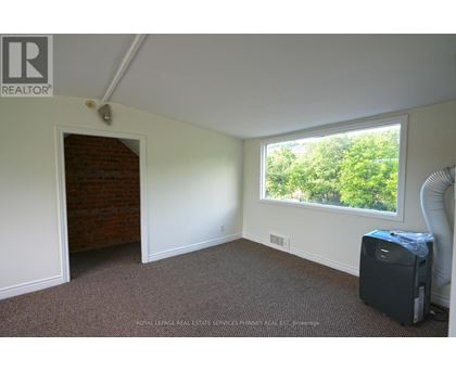 A room with a window and a door leading to a hallway.