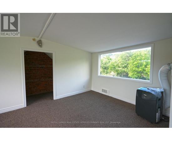 A room with a window and a door leading to a hallway.