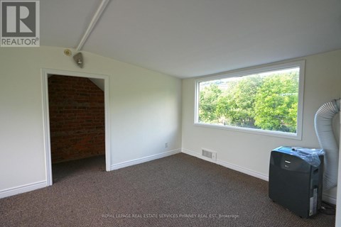 A room with a window and a door leading to a hallway.