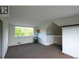 A room with a carpeted floor and a window with a view of trees.