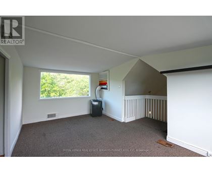 A room with a carpeted floor and a window with a view of trees.