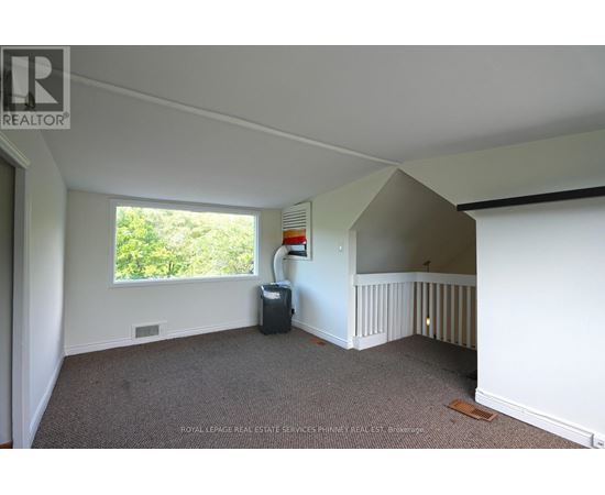 A room with a carpeted floor and a window with a view of trees.
