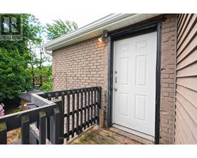 A white door is on a brick house with a black fence.