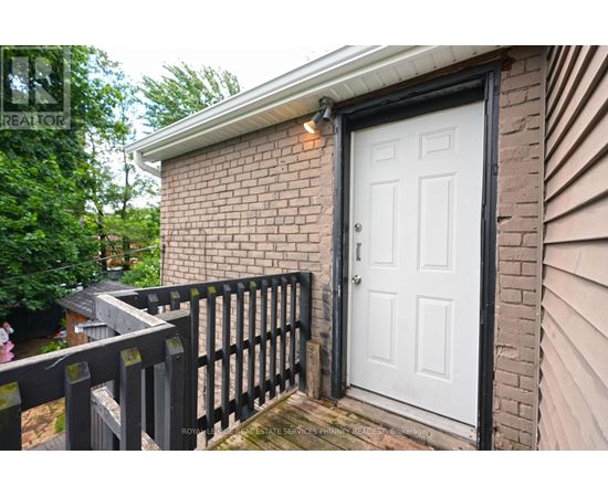 A white door is on a brick house with a black fence.