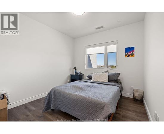 A bedroom with a bed, nightstand, and window.