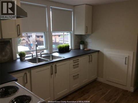A kitchen with white cabinets and a black countertop.