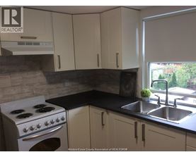 A kitchen with a stove, sink, and cabinets.