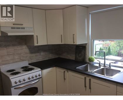 A kitchen with a stove, sink, and cabinets.