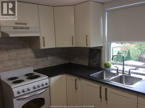 A kitchen with a stove, sink, and cabinets.