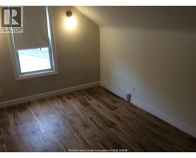 A room with a window and wooden flooring.