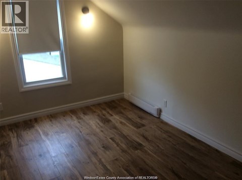 A room with a window and wooden flooring.
