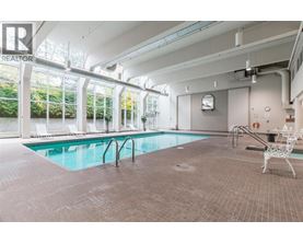 A large indoor swimming pool with a chair and a table nearby.