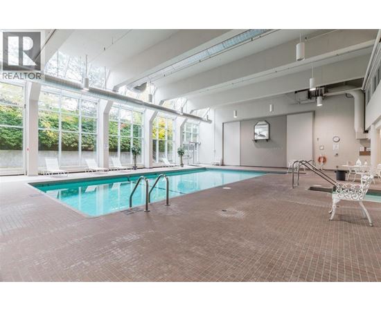 A large indoor swimming pool with a chair and a table nearby.