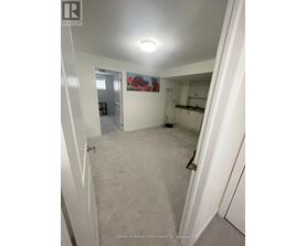 A bedroom with white walls and carpeting.