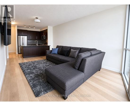 A living room with a grey couch and a black speaker.