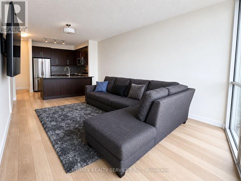 A living room with a grey couch and a black speaker.