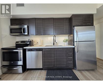 A modern kitchen with stainless steel appliances and dark wood cabinets.