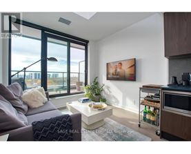 A living room with a grey couch, a white coffee table, and a painting on the wall.