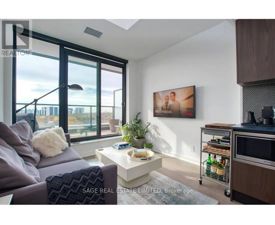 A living room with a grey couch, a white coffee table, and a painting on the wall.