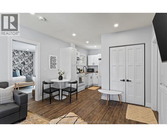 A modern kitchen with white cabinets and a black and white patterned wallpaper in the background.