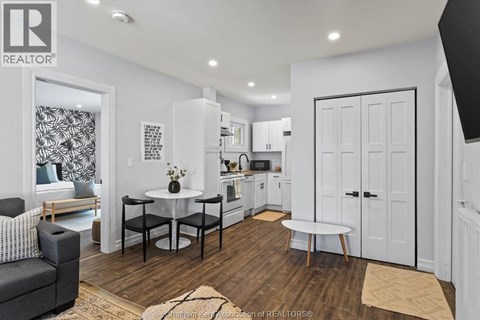 A modern kitchen with white cabinets and a black and white patterned wallpaper in the background.